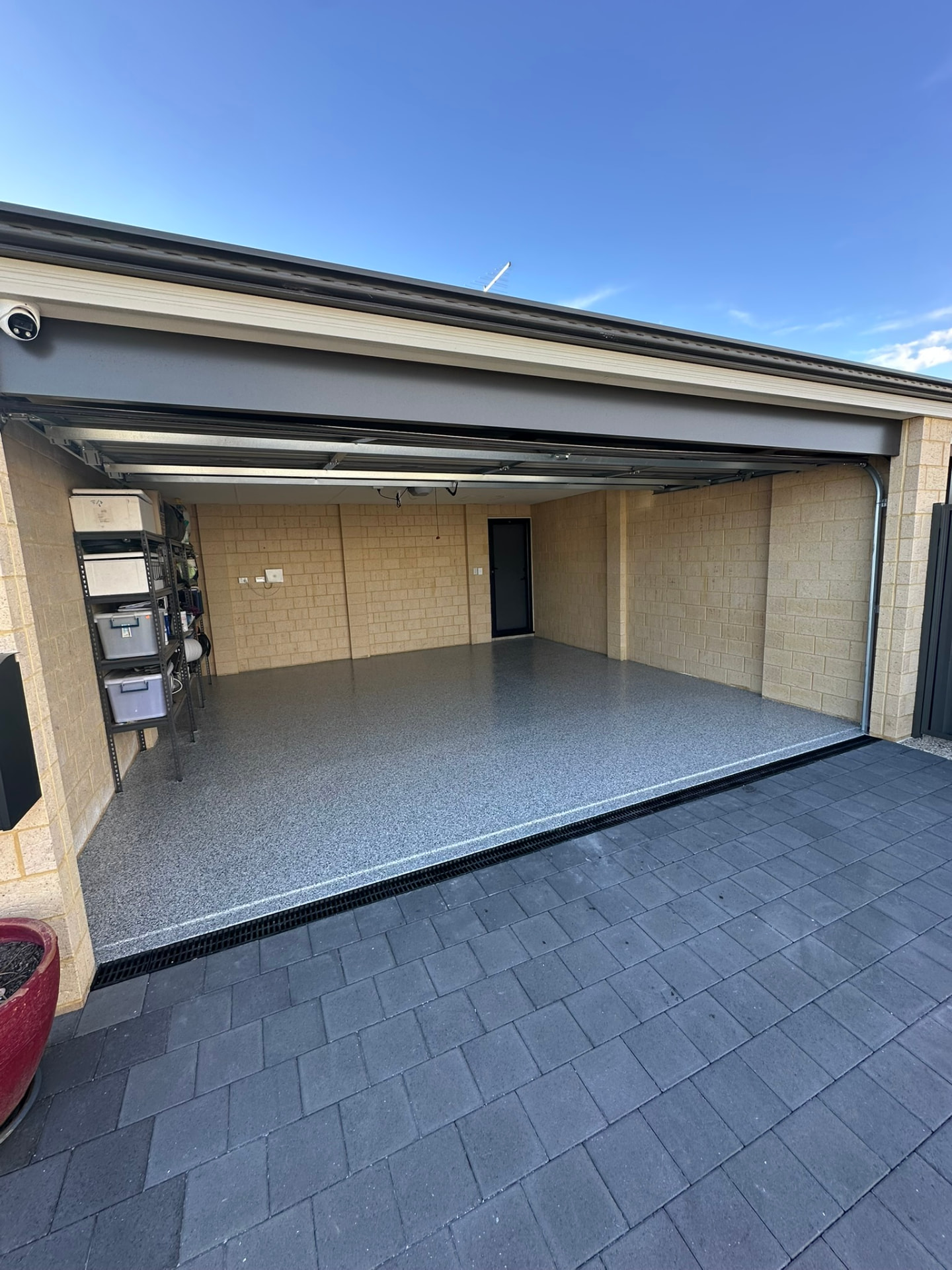 Completed garage with grey flake epoxy flooring and charcoal pavers